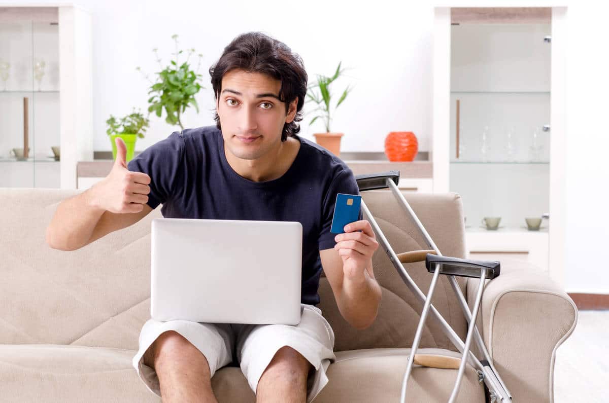 guy with broken foot_paying_with_credit_card_online