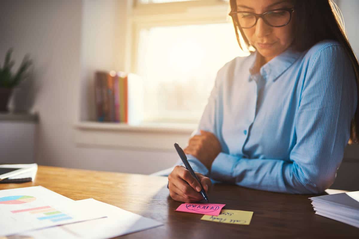 Business woman writing notes on post it in pink and yellow colours